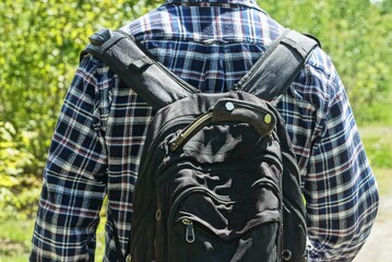 one man in a colored shirt with a black backpack on his back on the street