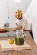 © Daniel - Close up. Woman squeezing lime in green juice. Reusable bamboo straw. Kitchen counter top.