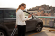 © JustLife - Businesswoman with luggage walking to the car on parking. Young woman going to business trip.