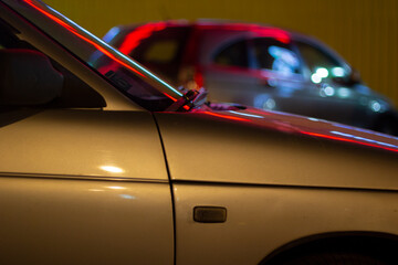 Cars at night in the lights from advertising. Car body details.