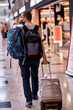 Masked passenger with luggage at the lobby of airport.Tourism during a pandemic of coronavirus. Blurred background. High quality photo