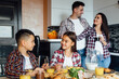 © Тарас Нагирняк - Family laughing around breakfast in kitchen while eating and children looking each other while sitting together.