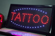 © ADDICTIVE STOCK - Illuminated signboard with neon word tattoo on shelf near decorations