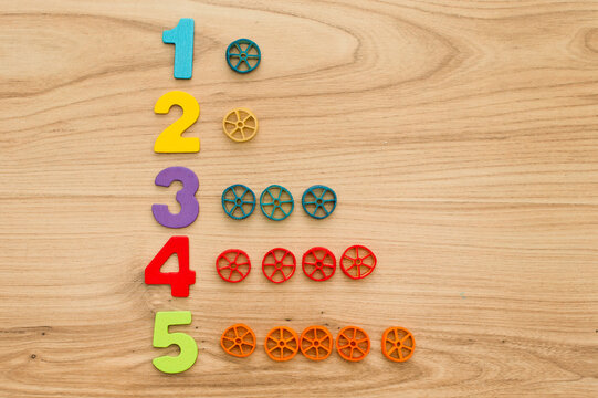 Math with fun. Counting uncooked pasta and marking with colored natural wood numbers.