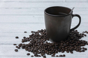 Black coffee in a brown coffee cup with roasted coffee beans.