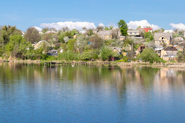 green coast of a beautiful small river with white clouds in reflection