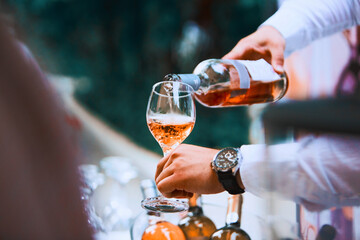 Wall Mural - The waiter serves rose and white wine from the wine bottle in the wine glass at an event.