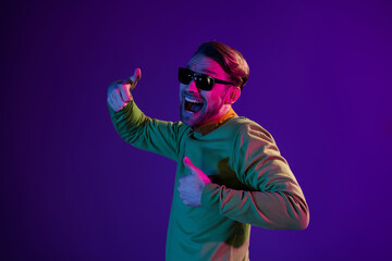 Sticker - Photo portrait of smiling man wearing sunglass showing thumb-up sign smiling cheerful isolated on dark purple color background