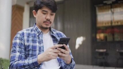 slow motion scene young middle eastern man hold smartphone to use by surfing the internet or read news on website or social media network at outside cafe for technology and. lifestyle concept