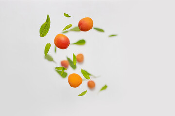 Falling juicy ripe apricot with green leaves isolated on white background. Flying defocusing slices of fruit.