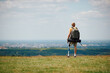 Rear view of disabled man with leg prosthesis enjoys the view from top of the hill while hiking in nature.