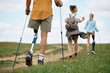 Rear view of disabled hiker with leg prosthesis walking with friends in nature.