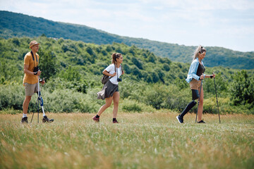 Young happy woman and her friends with leg disabilities enjoy in nordic walking in nature.