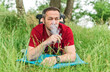 © bogdan vacarciuc - Man lying in the grass and smoking an electronic cigarette.