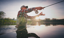 Fly Fisherman Stands In The Water And Casts The Fly With Fishing Rod Using Roll Cast With Lot Of Splashes