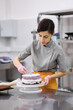 © Anischenko - A bright pastry chef girl is engaged in the preparation of a cake