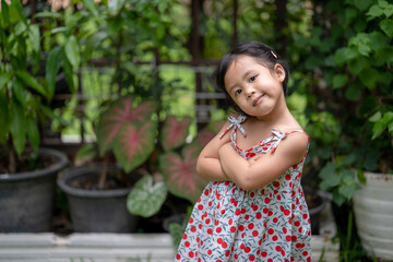 Wall Mural - Girl with happy face expression standing arms crossed at garden.