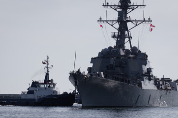 WARSHIP - US Navy guided missile destroyer maneuvers in the port assisted by a tugboat 

