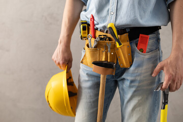 Canvas Print - Man worker holding construction helmet and hammer tool. Male hand and construction tools