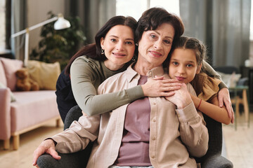 Poster - Affectionate females of three generations standing in front of camera