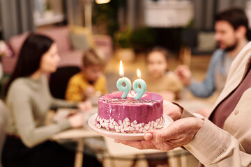 Poster - hand of mature woman holding birthday cake with two nine-shaped candles