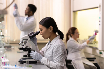 Sticker - Chinese female scientist looking in microscope in laboratory