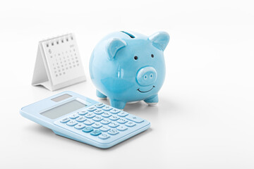 Piggy bank with blue calculator and calendar on white background