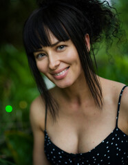 Wall Mural - Close-up portrait of a young elegant lady.A young smiling woman with natural make-up and dark hair in the garden. Portrait Photography.-Picture.