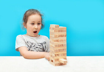 puzzle made of wooden blocks. a little girl plays with a board game made of wooden bars