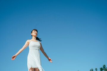 空と白いワンピースの踊る女性（深呼吸）
