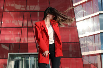 Young woman in a jacket on the background of glass building