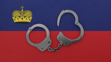 A half opened steel handcuff in center on top of the national flag of Liechtenstein