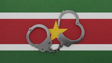 A half opened steel handcuff in center on top of the national flag of Suriname