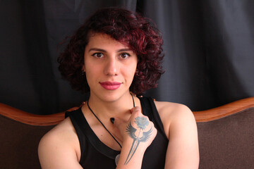 Wall Mural - Beautiful, young redhead transgender man in transition wearing a black dress and makeup in the studio looking directly at the camera