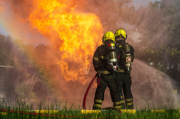 firefighters wearing fire fighter suit for safety and using twirl water extinguisher for fighting the fire flame in emergency situation.. - Safety Firefighter and industrial concept.