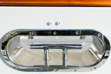 Stainless steel mooring bollard on the white hull of the yacht.