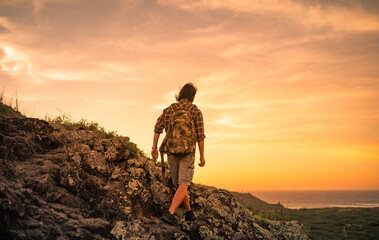 Male hiker climbing up the edge of a mountain. Adventure hiking concept. 