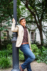 Leaning on a pole a young handsome guy is cheerfully looking at you..