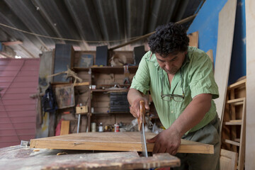 Mexican carpenter cutting wood with saw