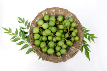 Wall Mural - Closeup of a bunch of ripe green tree fruit in the basket with leaves isolated on white background