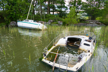 Stockholm, Sweden Two abandoned sailboats sit in shallow water in Lake Malaren.