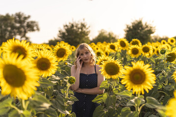 Poster - Beautiful view of a girl posing next to sunflowers growing in the field on a summer day