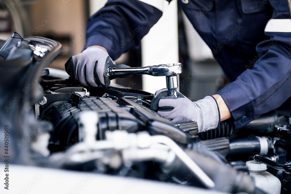 Professional mechanic working on the engine of the car in the garage. Car repair service. The concept of checking the readiness of the car before leaving. - obrazy, fototapety, plakaty 