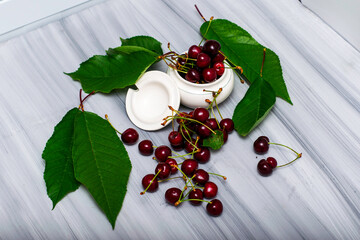 Wall Mural - a cup of cherries and cherry leaves on a white painted wooden table