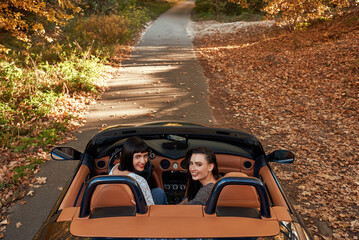 Rear view of two women friends in cabliolet looking back