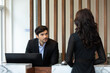 Friendly handsome man hotel receptionist in a stylish luxury hotel welcome and helping a female client at the front desk