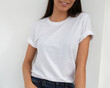 Tshirt mockup, front view of unrecognizable woman wearing white tshirt. Copy space on empty area on her t-shirt for design or inscription. Fashion lifestyle mock up of white tshirt. T-shirt template.