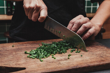 Wall Mural - Chef chopping green onion on a wooden table