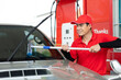Man worker in red uniform using sponge  clean windscreen and checking wiper blade of car while representing high quality service of gas fuel station
