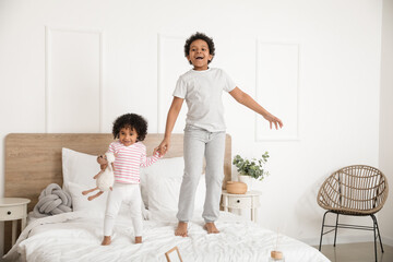 Wall Mural - African-American children jumping on bed in room